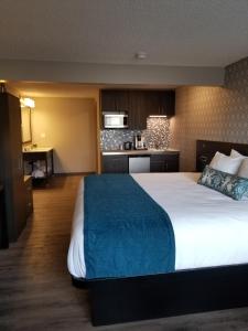 a hotel room with a large bed and a kitchen at The Hotel Y, a Dazzler Select by Wyndham in Yakima