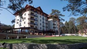 a large white building with a green field in front of it at Hotel Buket Zlatibor in Zlatibor