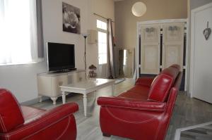 Le Comptoir des Ecoliers في Gémozac: غرفة معيشة مع كرسيين حمر وتلفزيون