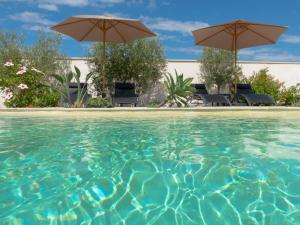 a swimming pool with chairs and umbrellas at Les Gites du Somail in Le Somail