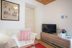 a living room with a television and a white chair at Alfama Charming Apt with 2 Free Bikes By TimeCooler in Lisbon