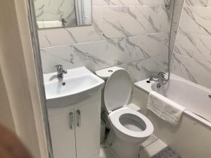 a white bathroom with a sink and a toilet and a tub at Luxury 2 Bedroom Flat in Abbey Wood, London in London