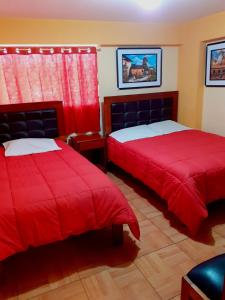 1 dormitorio con 2 camas con sábanas rojas y ventana en Hostal kuntur cusco, en Cusco