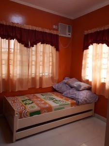 - un petit lit dans une chambre avec fenêtres dans l'établissement Modern House Staycation in Bacolod, à Bacolod