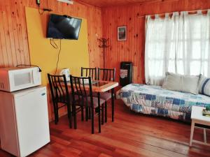 a room with a bed and a table and a microwave at Cabañas Las Golondrinas in Potrerillos