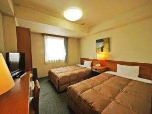 Cette chambre comprend deux lits et une télévision. dans l'établissement Hotel Route-Inn Yokkaichi, à Yokkaichi