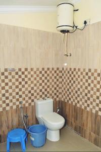 a bathroom with a toilet and a blue stool at Bruton resorts in Kodaikānāl