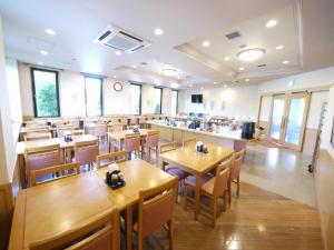 a dining room with wooden tables and chairs at Hotel Route-Inn Tajimi Inter in Tajimi