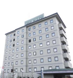 un grand bâtiment blanc avec un hôtel dans l'établissement Hotel Route-Inn Tajimi Inter, à Tajimi