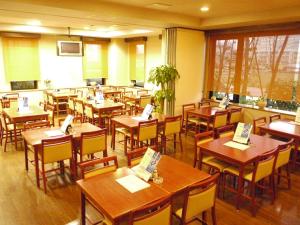 a restaurant with wooden tables and chairs in a room at Hotel Route-Inn Gifukencho Minami in Gifu