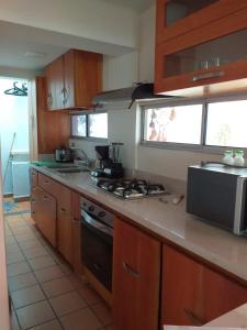 a kitchen with wooden cabinets and a stove top oven at Cabaña Ciudadela Premium San Jeronimo in San Jerónimo