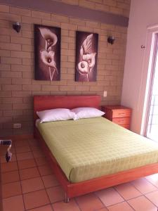 サン・ヘロニモにあるCabaña Ciudadela Premium San Jeronimoのベッドルーム1室(壁に2枚の写真が飾られたベッド1台付)