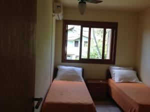 two beds in a room with a window at Praia Brava Apto 2 dorms Vista ao Mar in Florianópolis