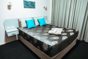 a bedroom with a bed with blue pillows at Copper City Motel in Cobar