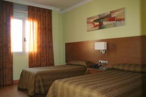 a hotel room with two beds and a window at Hotel 4C Puerta Europa in Madrid +8 photos