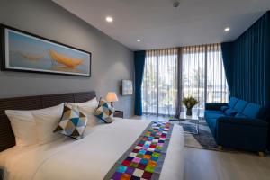 um quarto com uma cama grande e um sofá azul em Beach Haven Suites Hội An Apartment em Hoi An