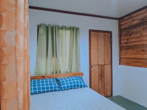 a bedroom with a bed with a window and a wooden door at NoBi's Inn, Port Barton in San Vicente