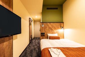 a hotel room with two beds and a flat screen tv at Rembrandt Style Sapporo in Sapporo