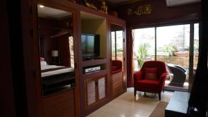 a living room with a tv and a red chair at LePrive Resort in Pattaya South