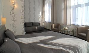 a bedroom with a bed and a couch and windows at Kurhotel Quellenhof in Bad Bertrich