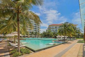a swimming pool with palm trees and a building at Clean & Quiet Villa - The Point Resort in Danang