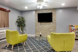 sala de estar con 2 sillas amarillas y TV en Super 8 by Wyndham San Antonio Pearl District Downtown en San Antonio