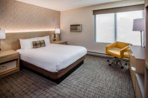 a hotel room with a bed and a yellow chair at Days Inn & Suites by Wyndham Duluth by the Mall in Duluth