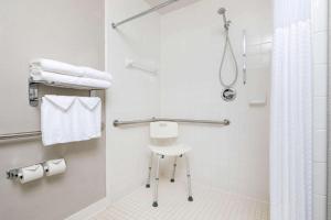a bathroom with a shower and a white stool at Microtel Inn & Suites by Wyndham Atlanta Buckhead Area in Atlanta