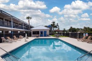 a pool at a hotel with chairs and a building at Travelodge by Wyndham Deltona in Deltona