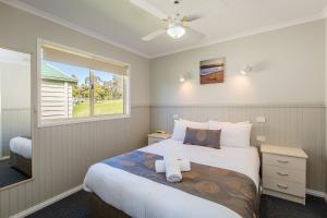 a hotel room with a bed, desk, and window at Discovery Parks - Lake Hume, New South Wales in Lake Hume