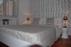 a white bed in a bedroom with two lamps at Leila's Apartment in Rome