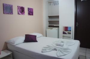 ein Schlafzimmer mit einem weißen Bett und einem Handtuch darauf in der Unterkunft Pousada das Gaivotas in Bombinhas + 21 Fotos