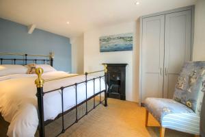 a bedroom with a bed and a fireplace and a chair at Chapel Cottage in Saint Mawes
