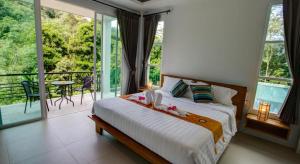 a bedroom with a bed and a balcony with a table at Kamala Amanah Hill in Kamala Beach