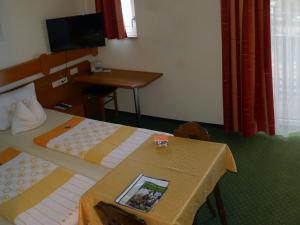 バート・ゲーグギングにあるHotel Fortunaのベッド2台、テーブル、テレビが備わるホテルルームです。