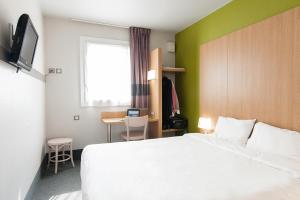 ブルージュにあるB&B HOTEL Bordeaux Lac sur Brugesの白いベッドとデスクが備わるホテルルームです。