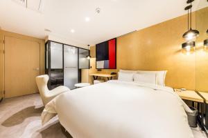a bedroom with a large white bed and a desk at Forestar Hotel Sinchon in Seoul