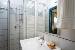 uma casa de banho com um lavatório, um chuveiro e um espelho. em La Casa Delle Querce em Acquaviva