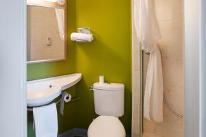 a green bathroom with a toilet and a sink at B&B HOTEL Brive-la-Gaillarde in Ussac