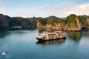 a boat on a river with mountains in the background at Mon Chéri Cruises in Ha Long