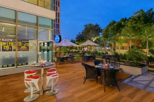 ein Restaurant mit Tischen und Stühlen auf einem Holzboden in der Unterkunft Novotel Ahmedabad in Ahmedabad