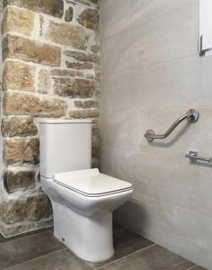 ein weißes WC im Bad mit einer Steinmauer in der Unterkunft Villa Antonis in Lákka