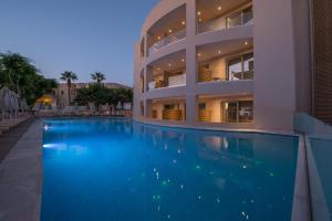 ein großes Gebäude mit einem Pool davor in der Unterkunft Cactus Beach Hotel in Stalida