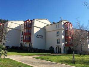 un gran edificio blanco con ventanas rojas en Studio tout confort proche Thermes & centre ville, en Lamalou-les-Bains