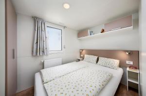 a small bedroom with a bed and a window at Knaus Campingpark Nürnberg in Nürnberg