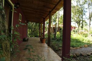 eine überdachte Veranda eines roten Hauses mit Topfpflanze in der Unterkunft Yateí-house in El Soberbio