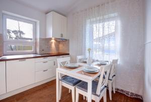 a white kitchen with a table and chairs and a window at Knaus Camping- und Ferienhauspark Rügen in Altenkirchen