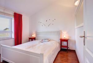 a white bedroom with a bed and two tables at Knaus Camping- und Ferienhauspark Rügen in Altenkirchen