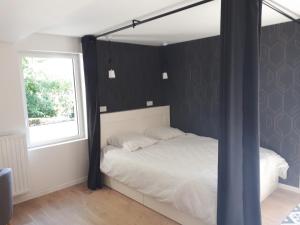 a bedroom with a black and white bed and a window at Appartement Pierres de Loire- Linge inclus -1er étage in La Bohalle