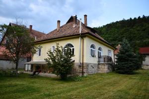 una casa vieja con un patio de hierba delante de ella en Halháza Erdészlak Apartman, en Sirok